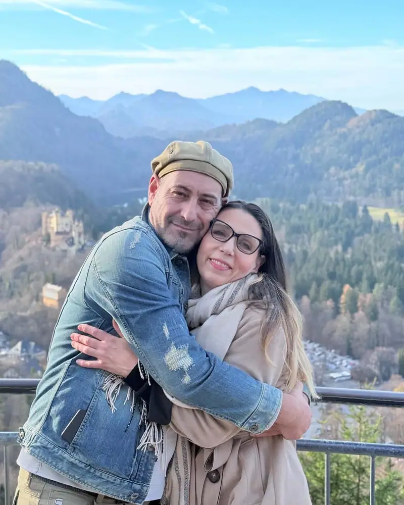 Gerry und Ivan, Ihre Gastgeber, Arm in Arm vor einem Alpenpanorama